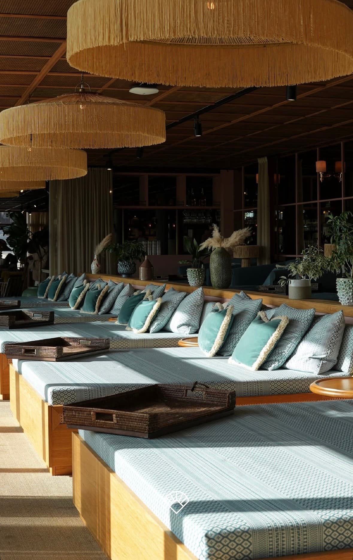 Lounge with daybeds, teal cushions and fringed lamps