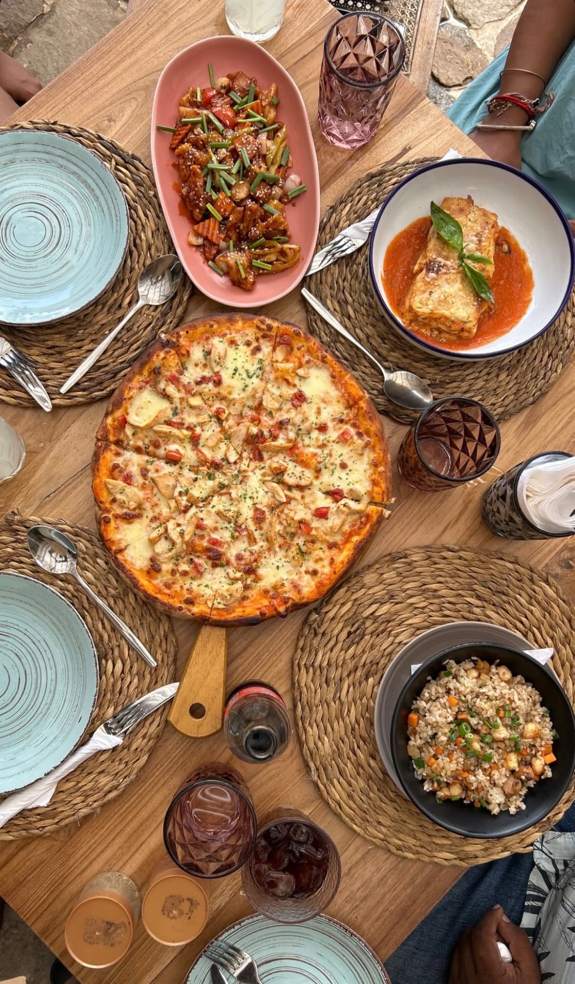 Pizza, lasagna and fried rice shared on a wooden table