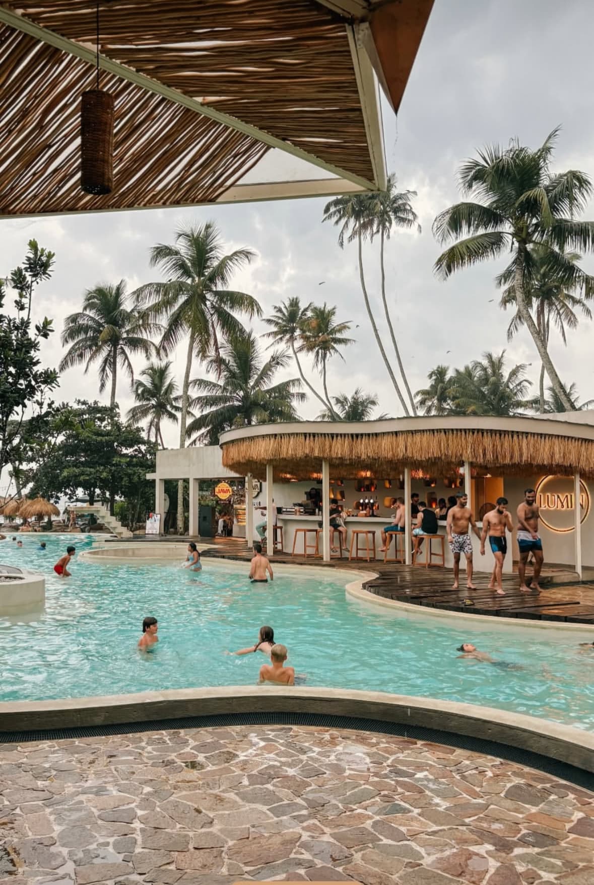 Pool bar under a thatched roof and palms