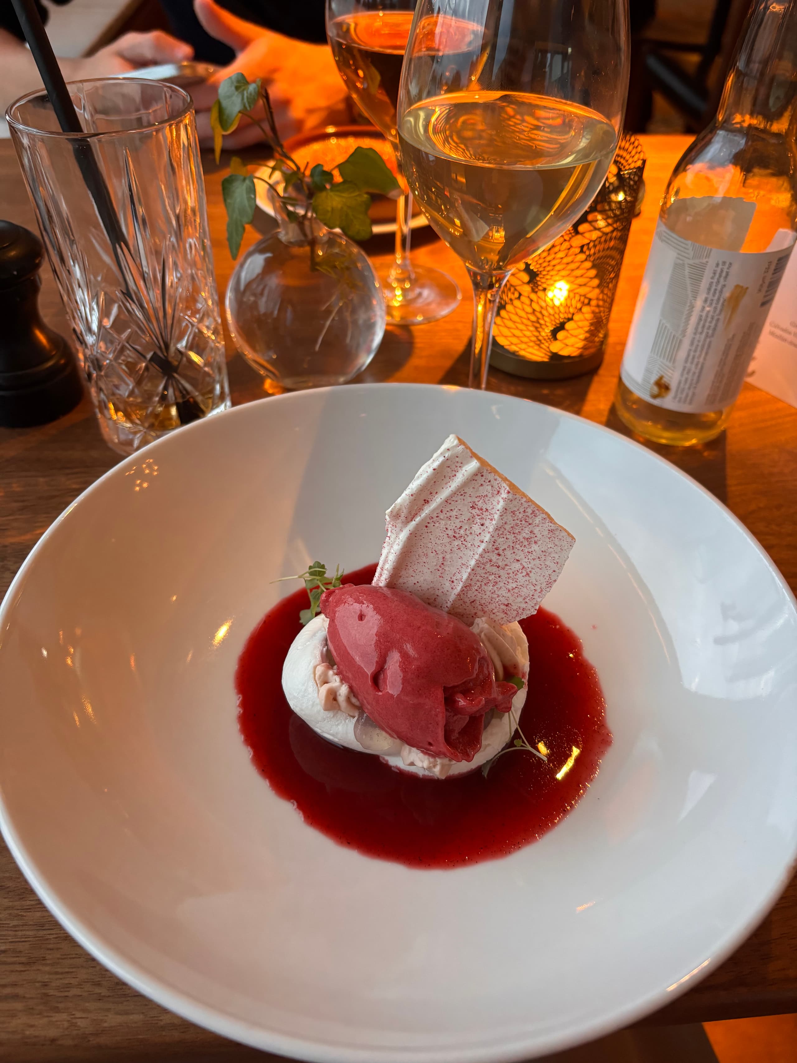 Berry sorbet dessert with meringue and a glass of white wine